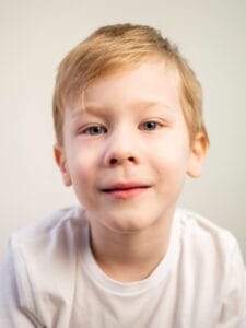 Niño de 8 años viendo a la cámara mientras espera pasar consulta con el optometrista infantil para examen de la vista