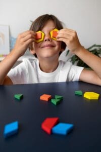 Niños de 8 años divirtiéndose con figuritas geométricas mientras realiza ejercicios de terapia visual en Opticalia Zaben
