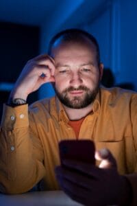 Hombre de 42 años viendo el móvil mientras tiene dificultades para leer por culpa de la presbicia no diagnosticada
